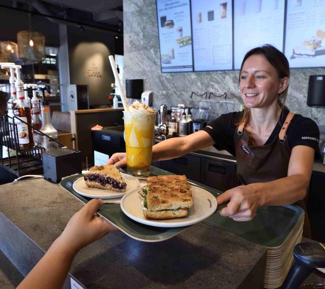 la photo montre une serveuse qui remet un plateau avec des produits Espresso House